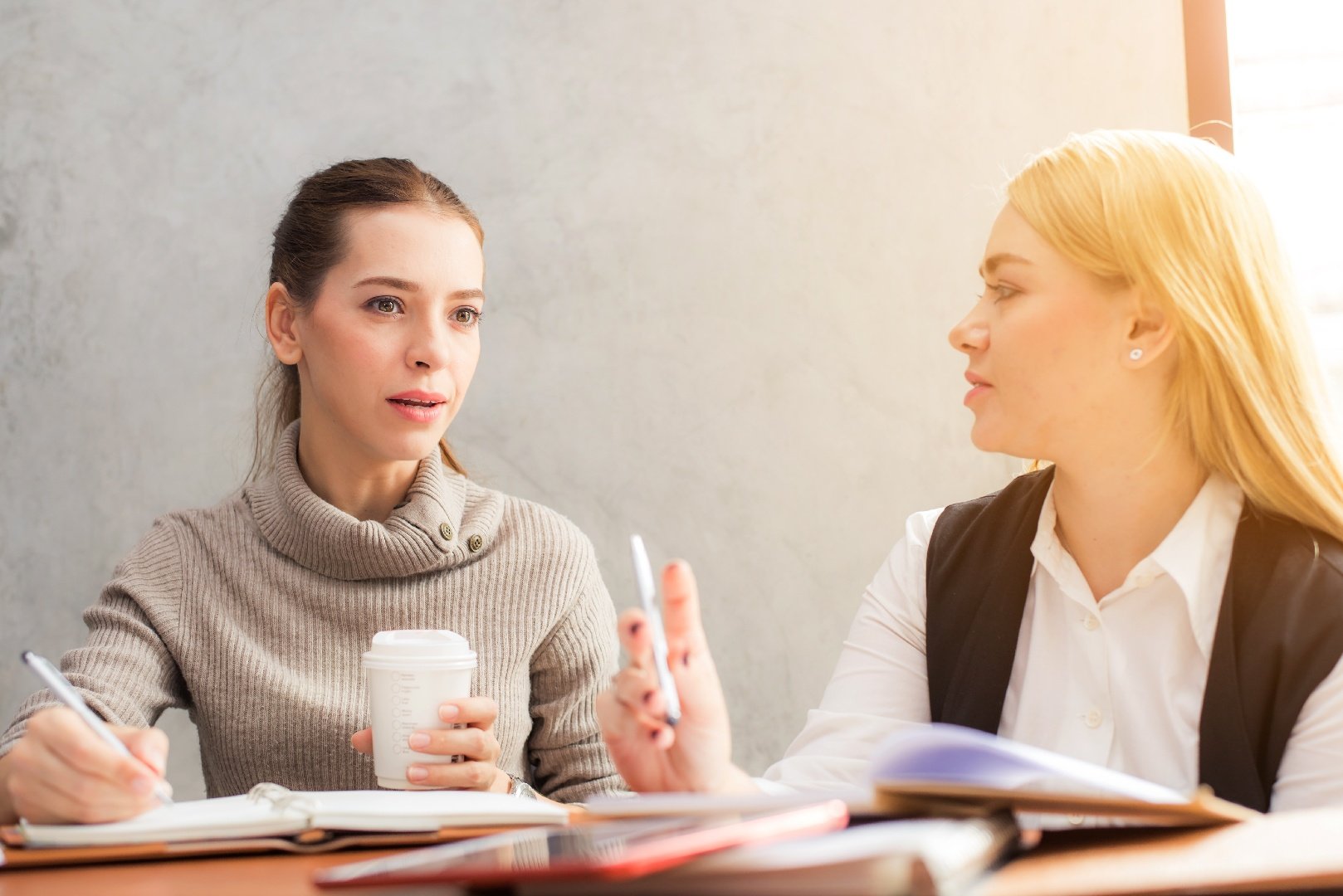 Two women sitting at a table making decisions over coffee.